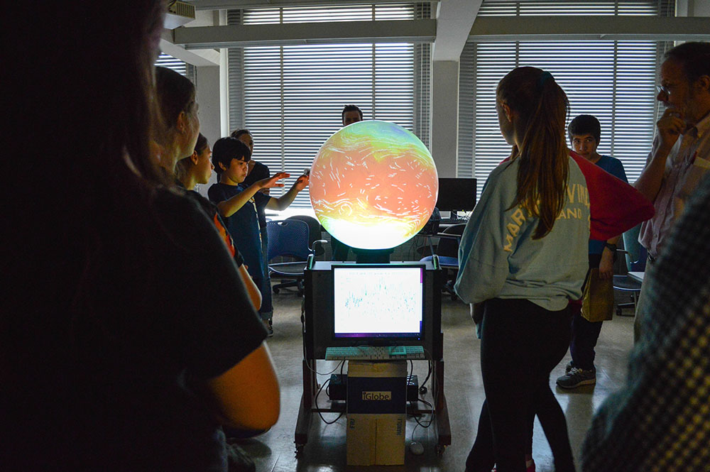 Local middle school students gather around the iGlobe for lessons in weather, climate, and oceanography.